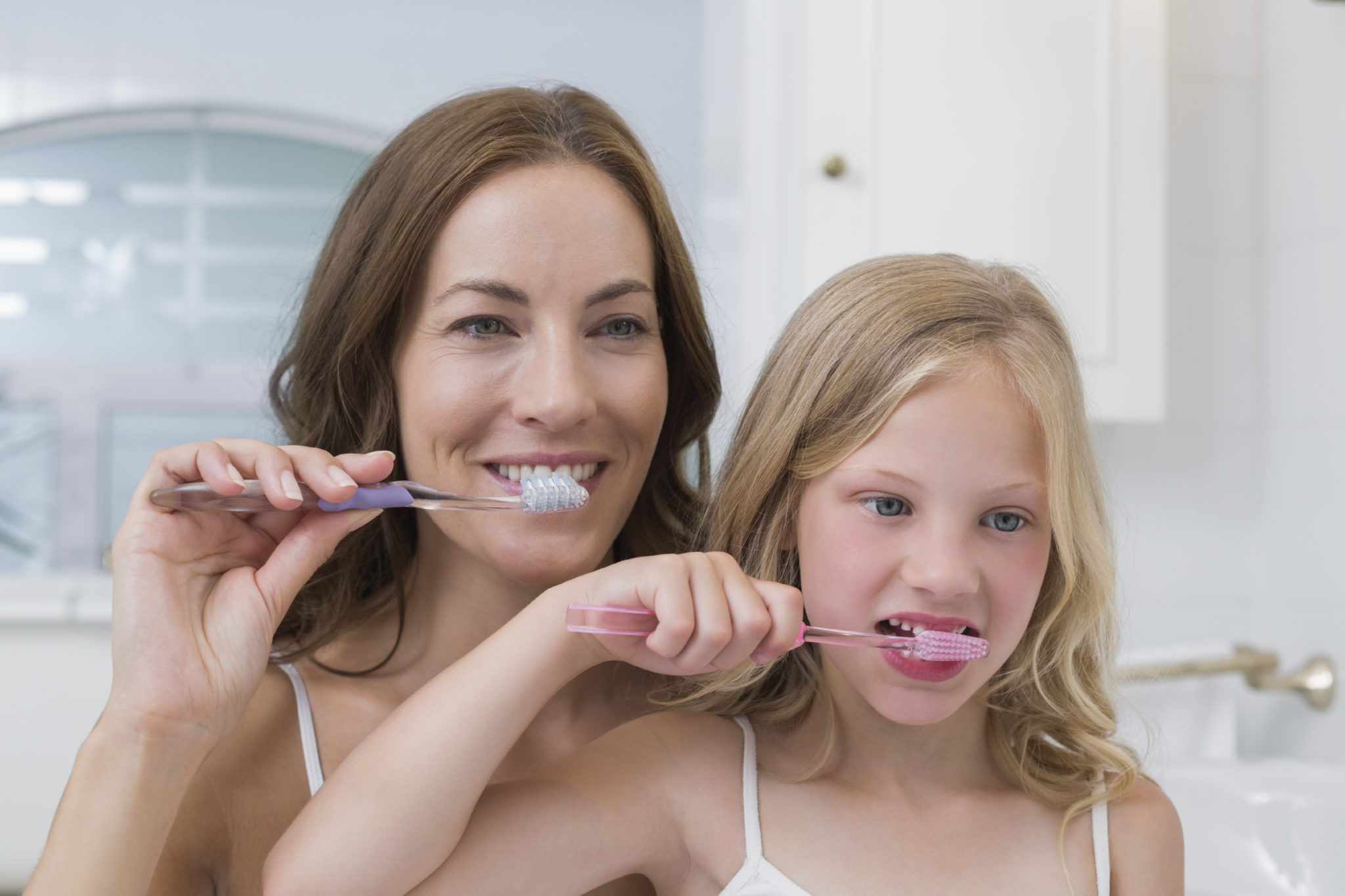 Mother-and-daughter-brushing-teeth-in-bathroom-000059728824_Large